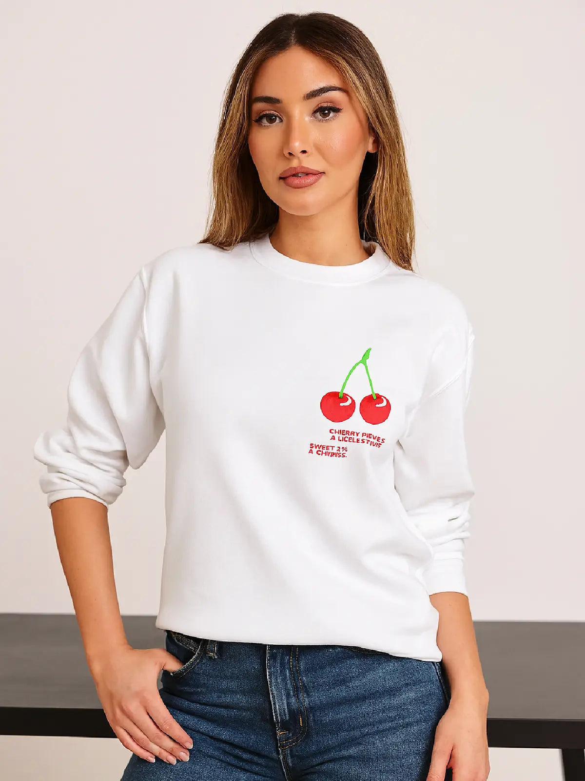 Woman wearing a white sweatshirt with cherry design and text.